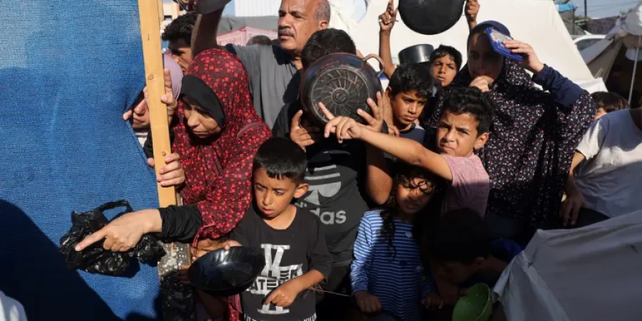 النازحون الفلسطينيون الذين فروا من منازلهم وسط الضربات الإسرائيلية، ينتظرون عند نقطة لتوزيع المواد الغذائية